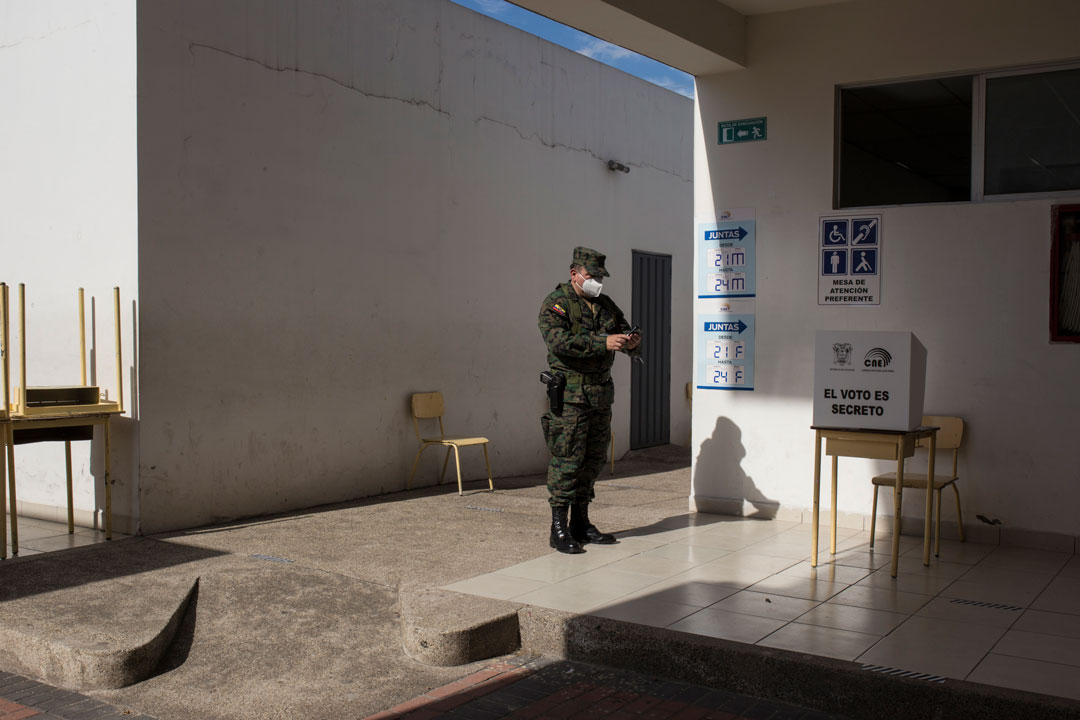 Un miembro de las fuerzas armadas, reporta a través de su teléfono celular cómo va la organización en la junta receptora del voto al que fue asignado.
